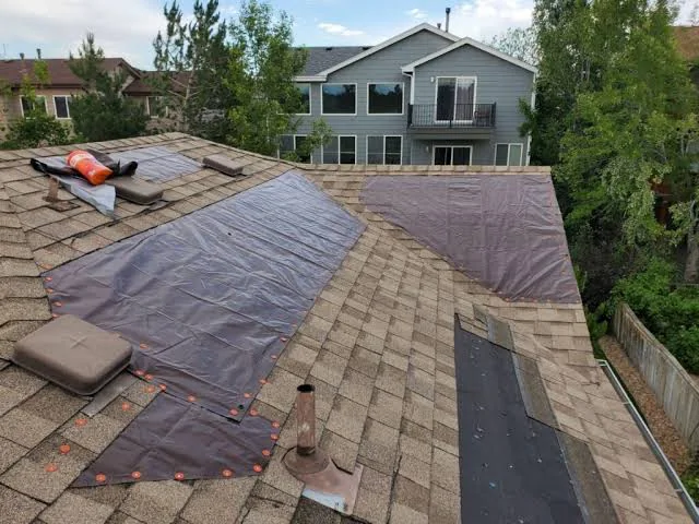 Two emergency tarps battened down over damaged slopes of a residential roof after a storm